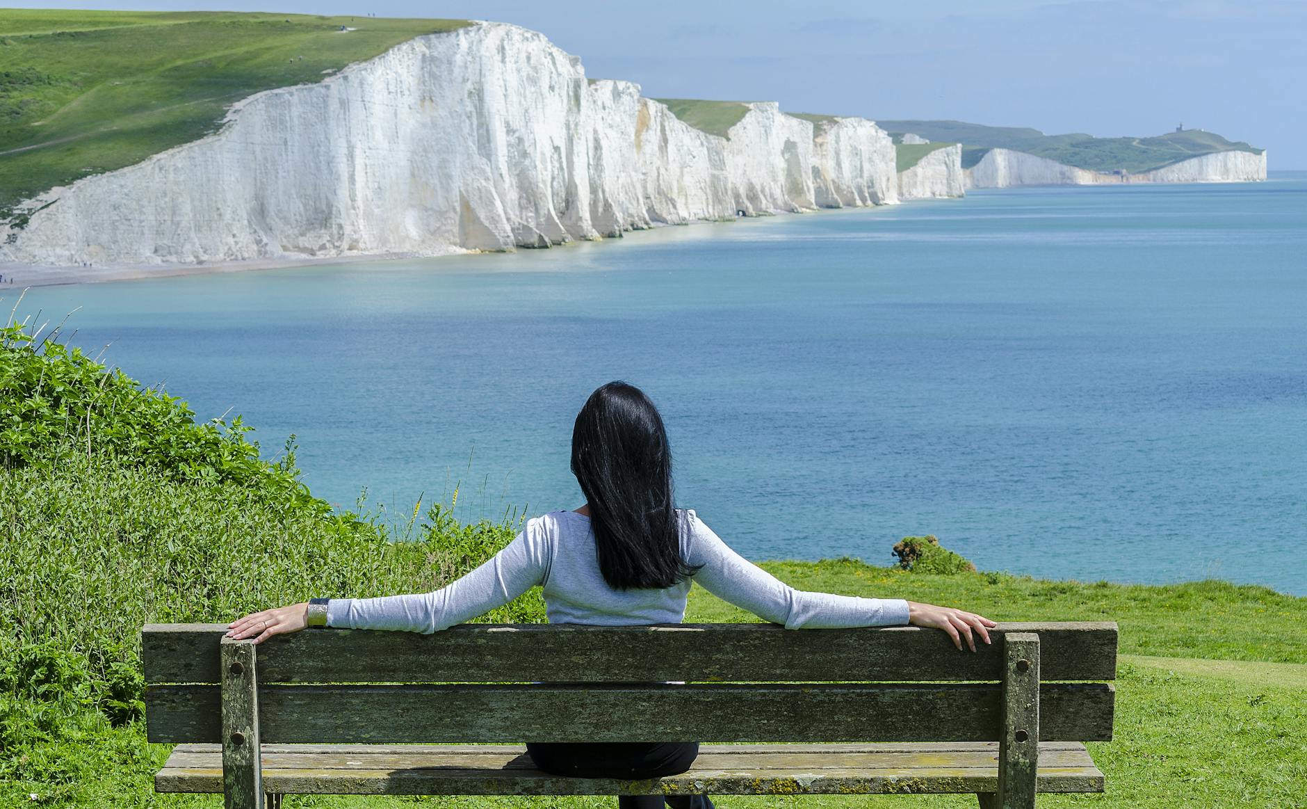 woman sat on cliff top on bench